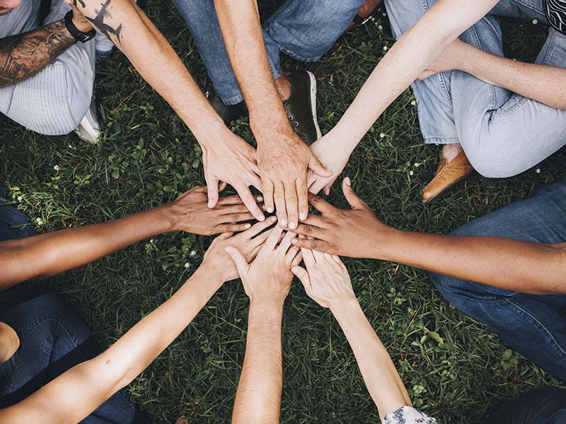 saap-800_0006_people-stacking-hands-together-park